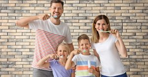 a family practices dentistry together by brushing their teeth