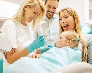 A blonde mom holds her daughter during their family dentistry appointment.