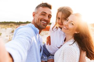 family smiling at the beach after visiting the dentist